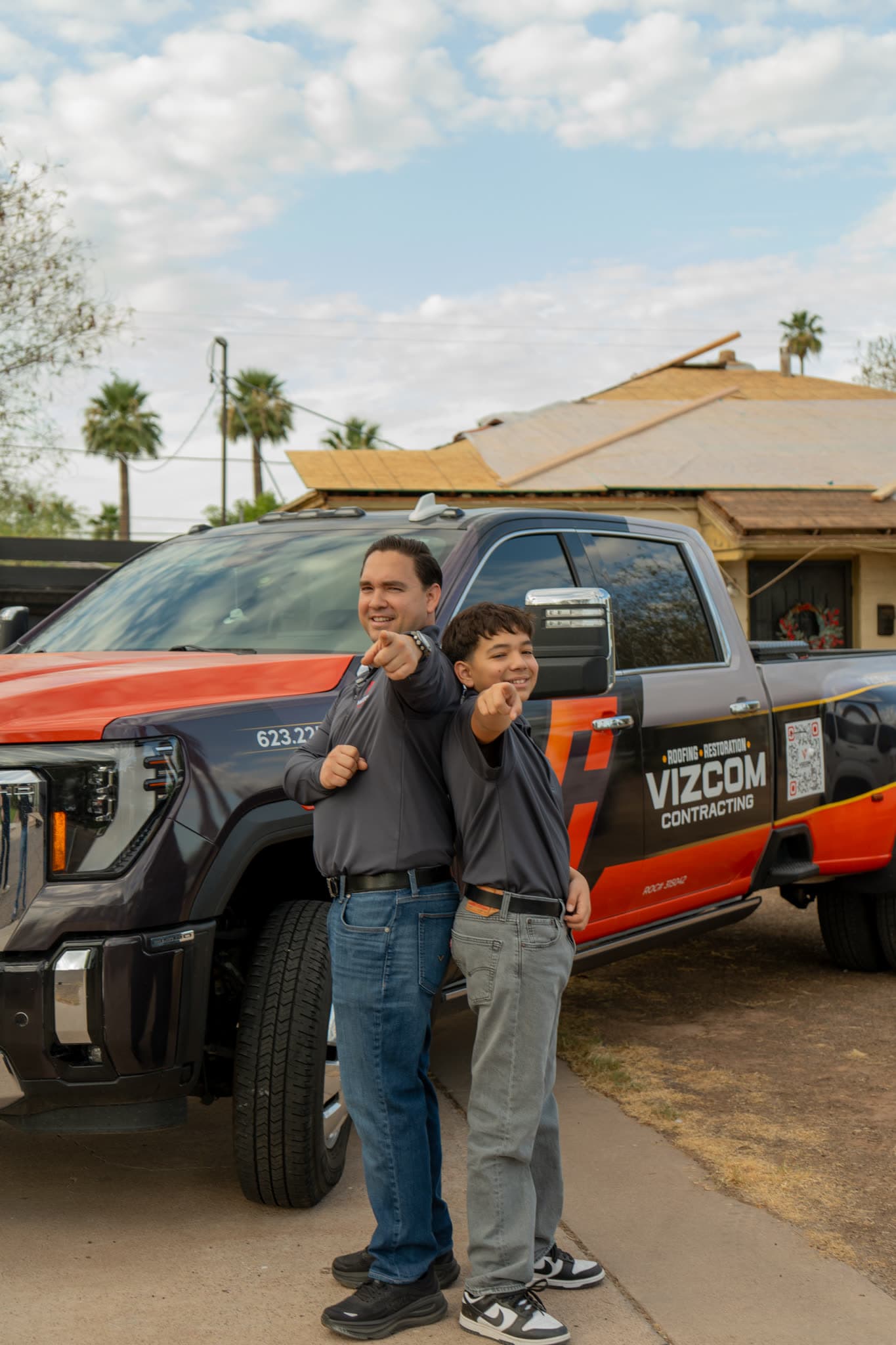 Omar Vizcarra and his son beside a wrapped Vizcom Contracting truck outside a house being reroofed.