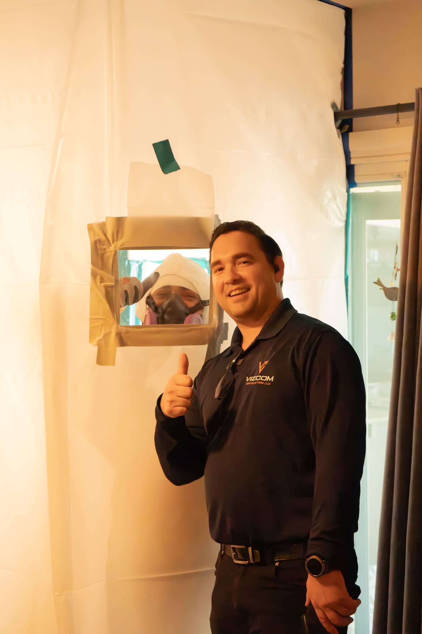 Vizcom Contracting team member beside a sealed containment while a crew member in a respirator works inside.