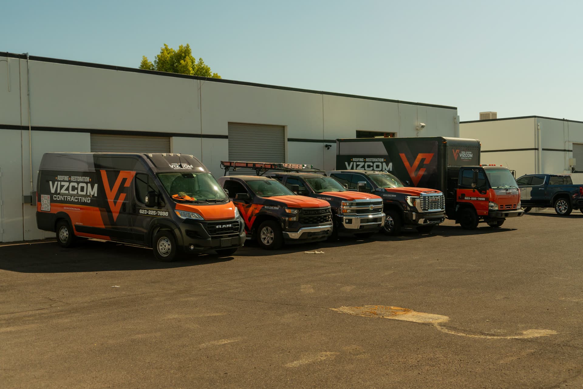 The Vizcom Contracting fleet of wrapped vans, trucks and a box truck parked outside the company warehouse.