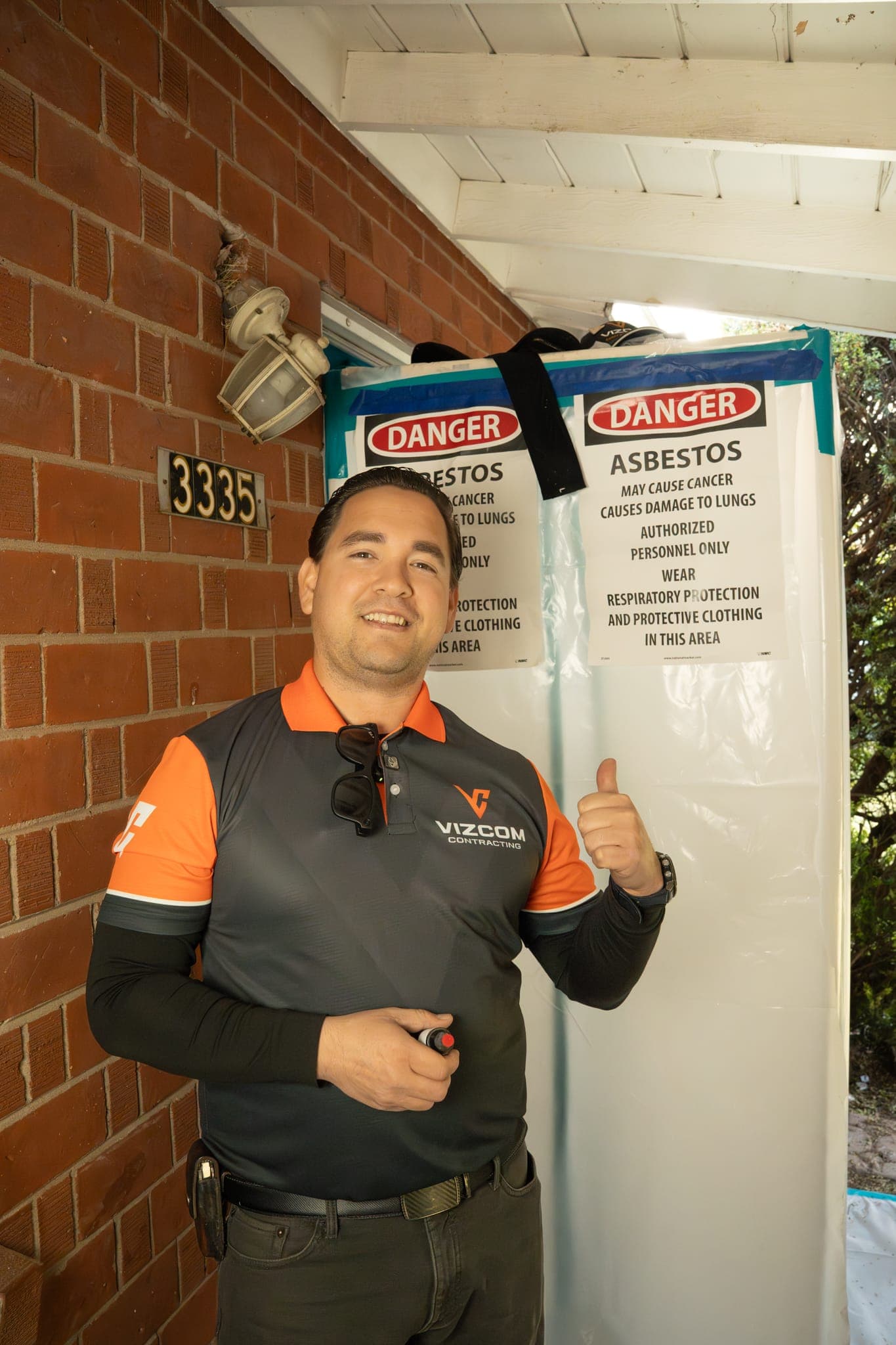 Posted asbestos danger signage at a sealed Vizcom Contracting containment entry.